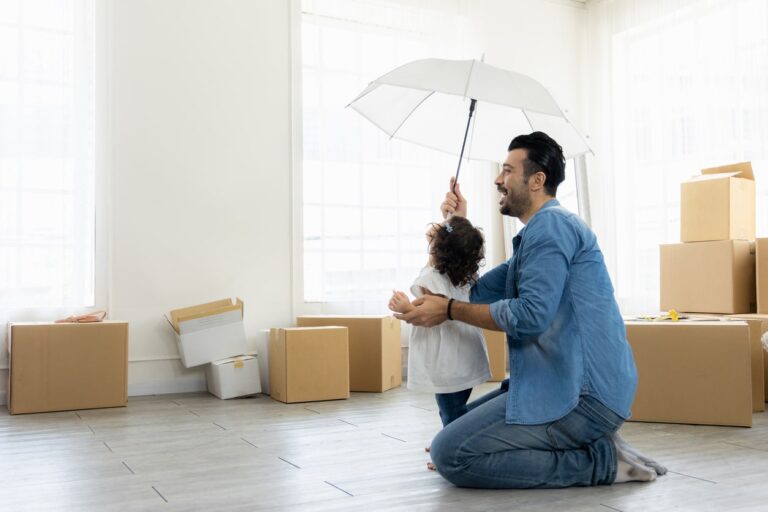 Happy moment family. Father and daughter relax in living room holding the white umbrella. Just moving new house many parcel box on the floor